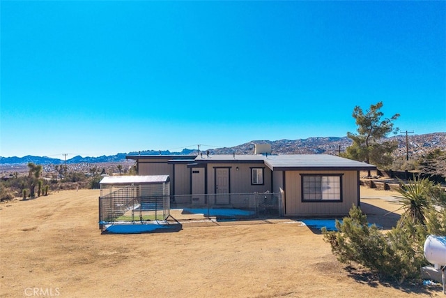 back of property featuring a mountain view and an outdoor structure