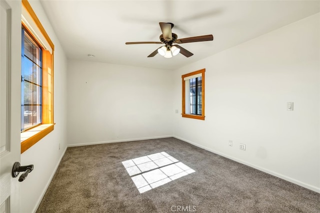 empty room with ceiling fan, a healthy amount of sunlight, and dark carpet