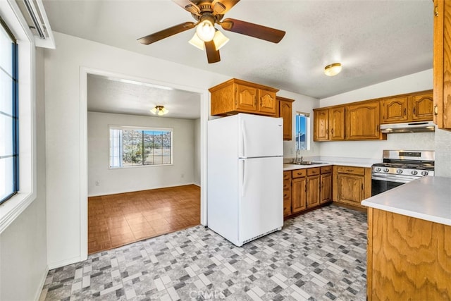 kitchen with sink, white refrigerator, ceiling fan, stainless steel gas range, and a textured ceiling