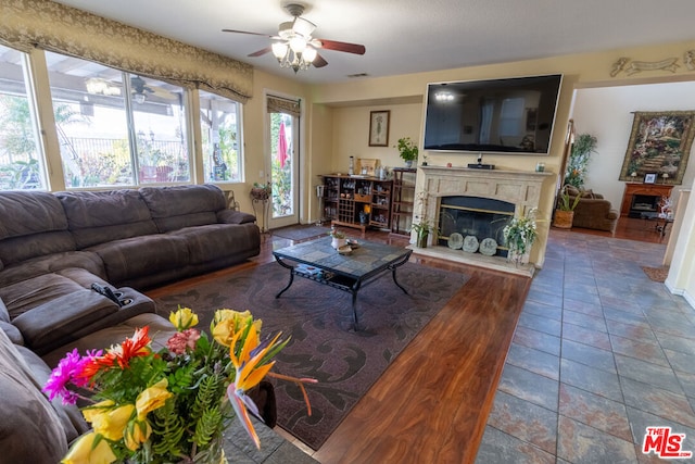 tiled living room featuring ceiling fan and a high end fireplace