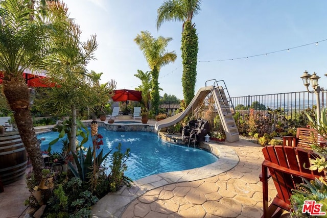 view of pool featuring an in ground hot tub, a water slide, and a patio area