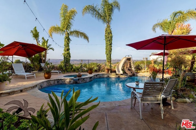 view of pool featuring an in ground hot tub, a water slide, and a patio