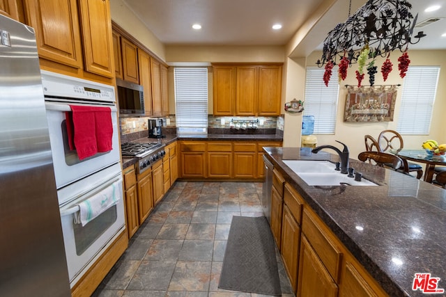 kitchen featuring tasteful backsplash, stainless steel appliances, sink, and hanging light fixtures