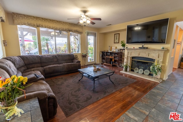 living room with ceiling fan and a high end fireplace