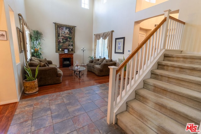 stairs with hardwood / wood-style flooring and a towering ceiling