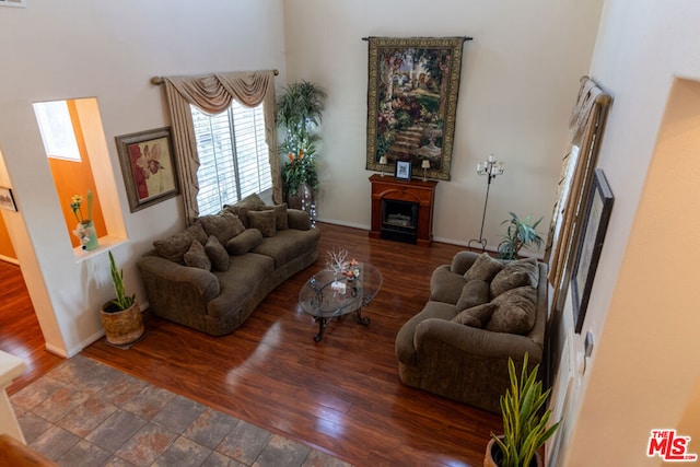 living room with dark wood-type flooring and a towering ceiling