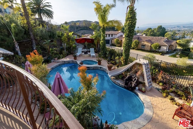 view of swimming pool featuring an in ground hot tub and a water slide