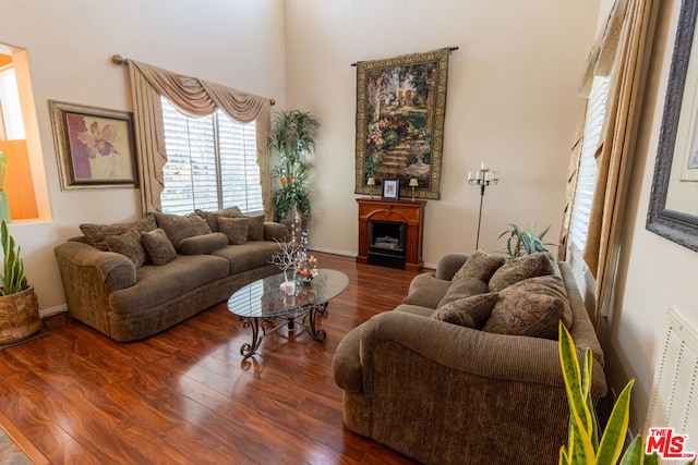 living room with dark hardwood / wood-style floors and a high ceiling