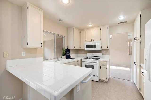 kitchen with sink, tile countertops, white appliances, and kitchen peninsula