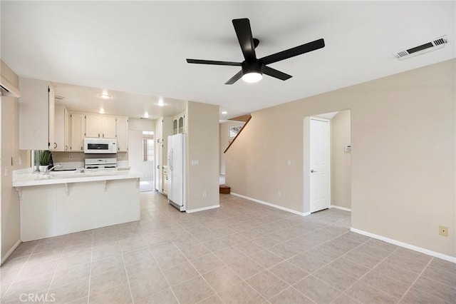 kitchen with a breakfast bar, white cabinetry, ceiling fan, kitchen peninsula, and white appliances