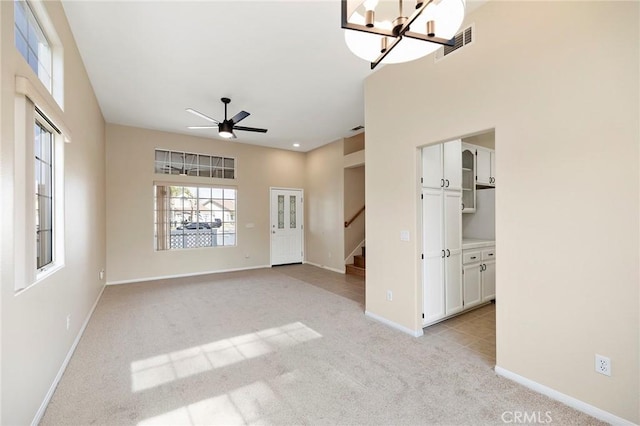 unfurnished room featuring ceiling fan with notable chandelier and light carpet