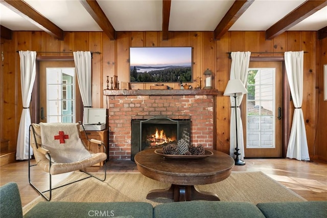 sitting room with light hardwood / wood-style flooring, beam ceiling, a fireplace, and wood walls