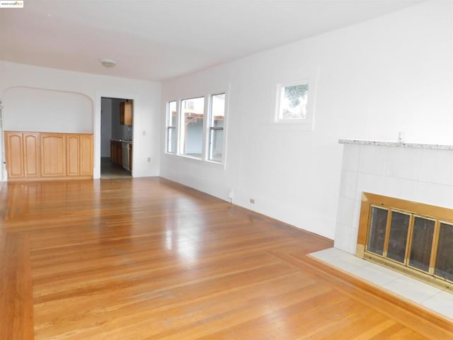 unfurnished living room featuring light hardwood / wood-style floors and a tile fireplace