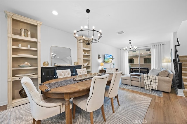 dining space with built in features, light hardwood / wood-style flooring, and a notable chandelier