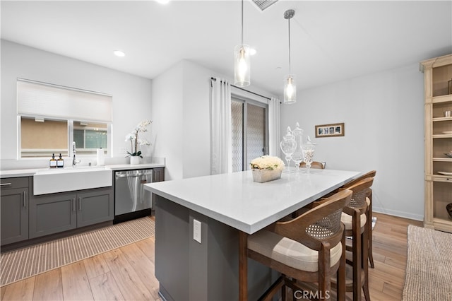 kitchen featuring sink, gray cabinetry, hanging light fixtures, stainless steel dishwasher, and light hardwood / wood-style floors