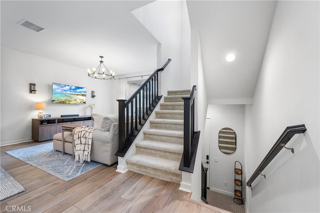 stairway with wood-type flooring and a chandelier