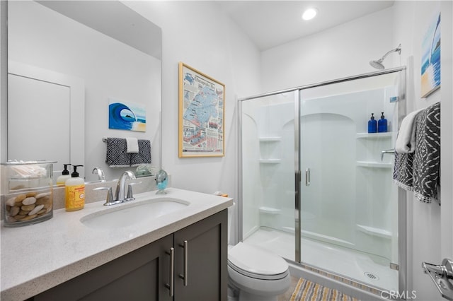 bathroom featuring vanity, toilet, and a shower with shower door