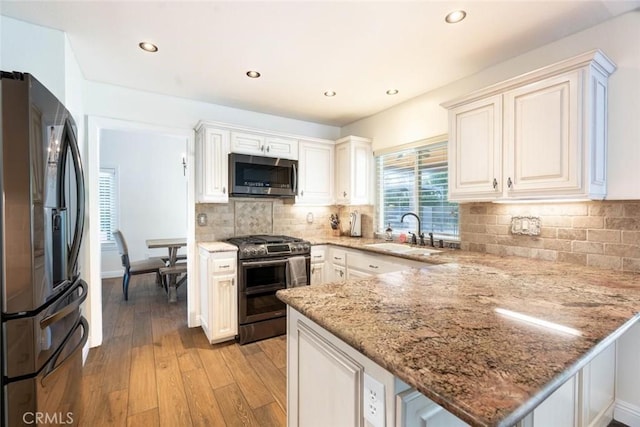 kitchen featuring white cabinetry, light stone counters, stainless steel appliances, and kitchen peninsula