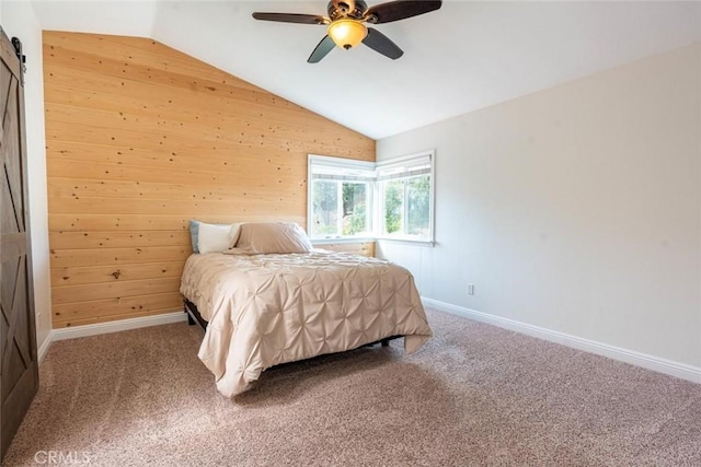 bedroom featuring a barn door, lofted ceiling, carpet, and wood walls