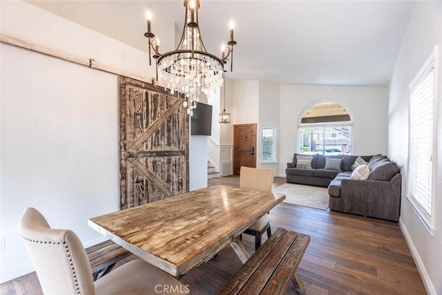 dining room featuring a barn door, dark hardwood / wood-style floors, and a chandelier