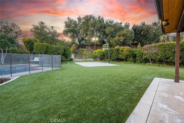 yard at dusk featuring a fenced in pool, basketball court, and a patio