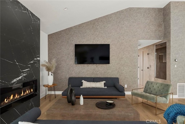 living room featuring hardwood / wood-style flooring, a fireplace, and high vaulted ceiling