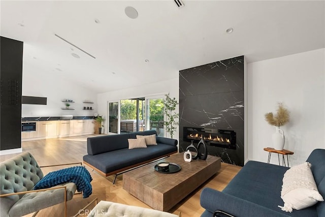 living room featuring lofted ceiling, a fireplace, and light hardwood / wood-style flooring