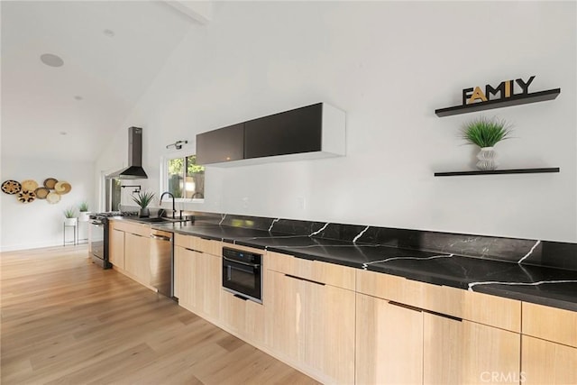 kitchen with wall chimney range hood, light brown cabinets, range, and black oven