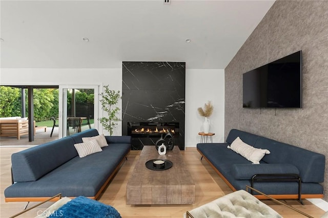 living room with lofted ceiling, light hardwood / wood-style flooring, and a premium fireplace