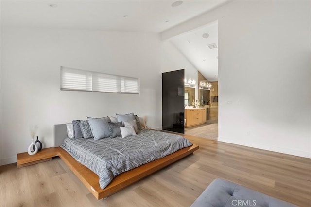 bedroom with lofted ceiling with beams, light hardwood / wood-style floors, and ensuite bathroom