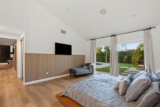 bedroom with high vaulted ceiling, light hardwood / wood-style floors, and access to outside