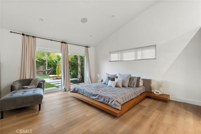 bedroom featuring light hardwood / wood-style flooring, access to outside, and high vaulted ceiling