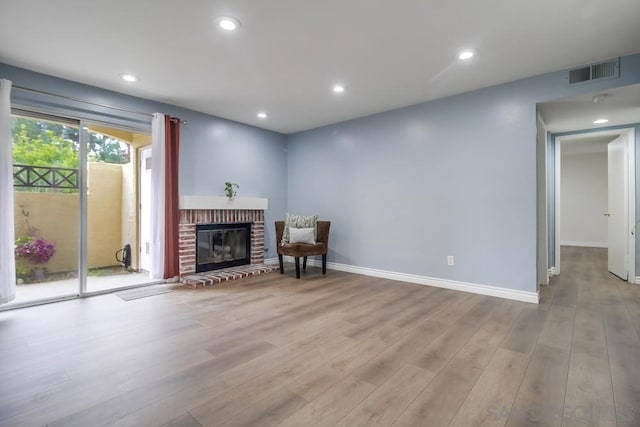 living room with a fireplace and light wood-type flooring