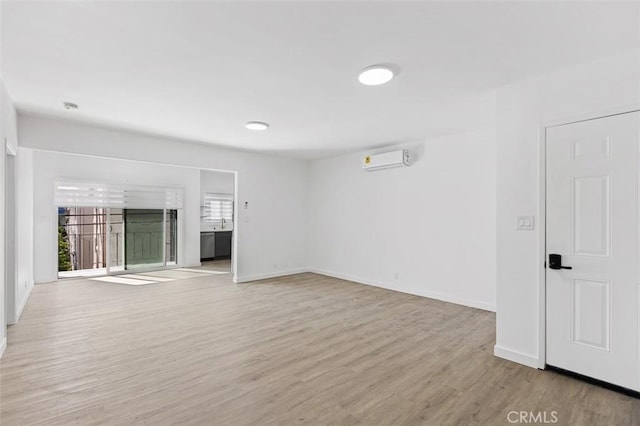 unfurnished living room with an AC wall unit and light hardwood / wood-style floors