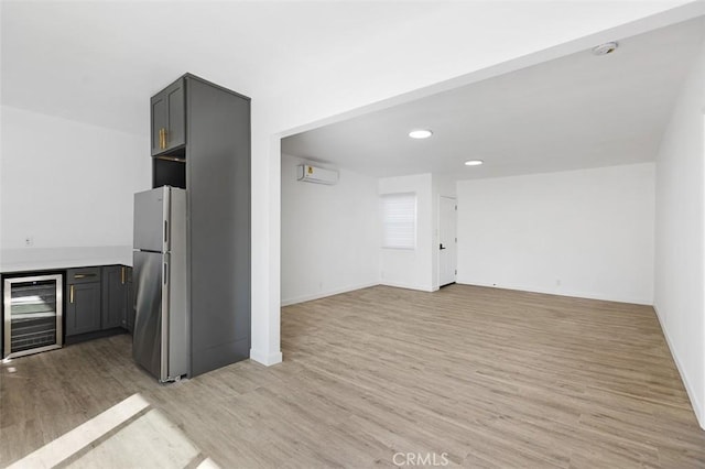 interior space featuring wine cooler, gray cabinetry, a wall mounted air conditioner, stainless steel fridge, and light hardwood / wood-style floors