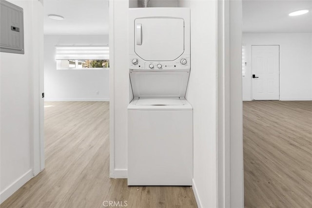 laundry area with stacked washer and dryer, light hardwood / wood-style flooring, and electric panel