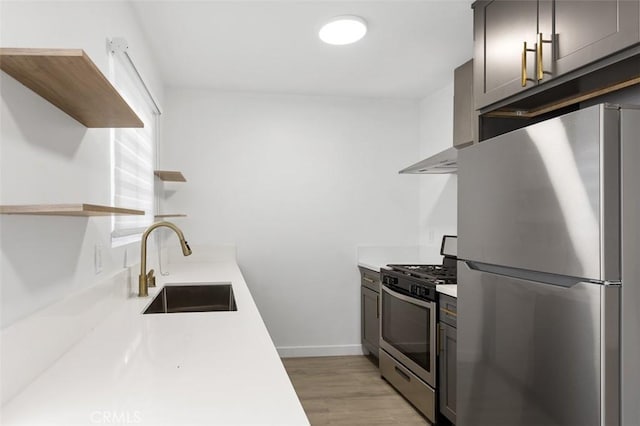 kitchen with stainless steel appliances, sink, wall chimney range hood, and light hardwood / wood-style floors