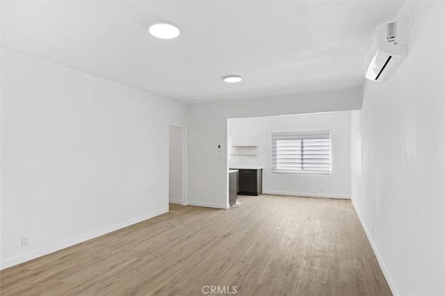 unfurnished living room with a wall mounted AC and light hardwood / wood-style floors