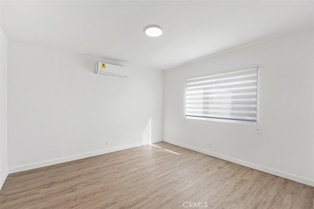 empty room with a wall mounted air conditioner and light hardwood / wood-style floors