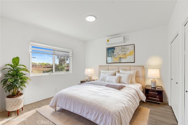 bedroom featuring a closet, light hardwood / wood-style flooring, and an AC wall unit