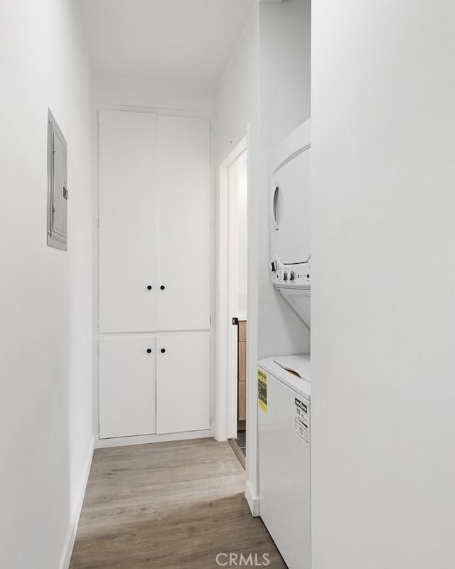 laundry area featuring stacked washer and dryer, electric panel, and light wood-type flooring