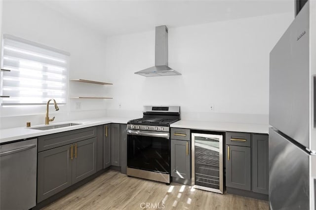 kitchen with wall chimney range hood, sink, gray cabinetry, stainless steel appliances, and wine cooler