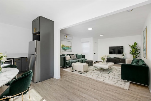 living room with a wall mounted air conditioner and light wood-type flooring