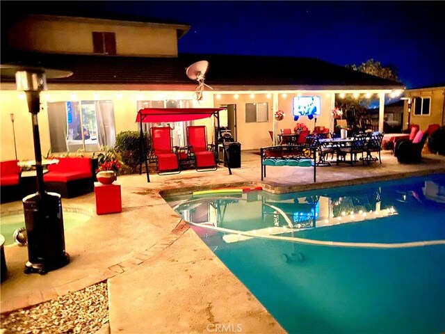 pool at twilight featuring a patio area