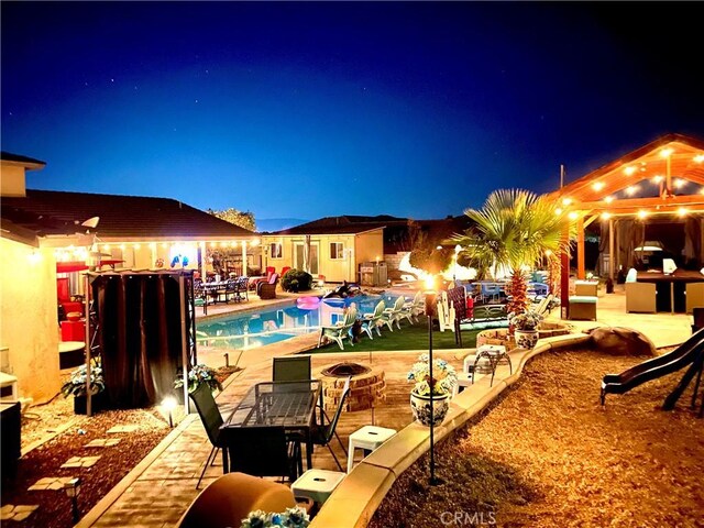 pool at twilight featuring a patio and a fire pit