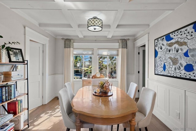 dining space featuring coffered ceiling, beam ceiling, and light hardwood / wood-style flooring