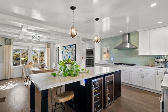 kitchen featuring pendant lighting, wall chimney range hood, white cabinets, and black gas cooktop