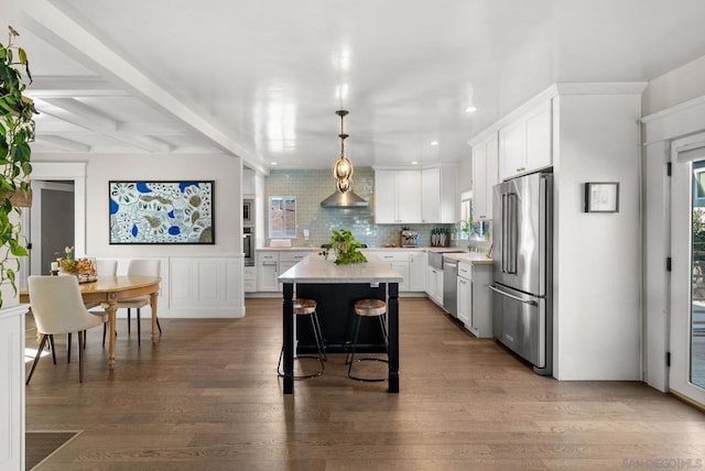 kitchen featuring pendant lighting, dark wood-type flooring, appliances with stainless steel finishes, white cabinetry, and a center island