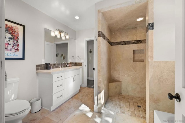 bathroom with tiled shower, vanity, and toilet