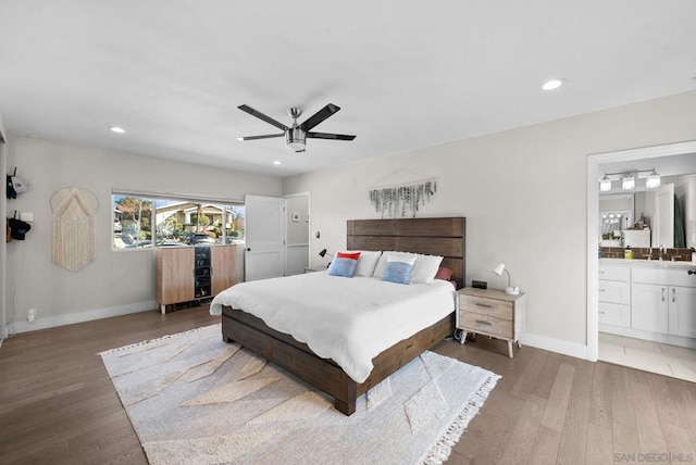 bedroom featuring ceiling fan, wood-type flooring, ensuite bathroom, and sink